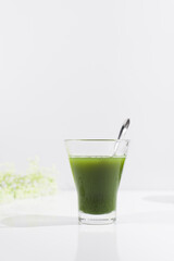 Un vaso de té verde matcha sobre una mesa blanca	