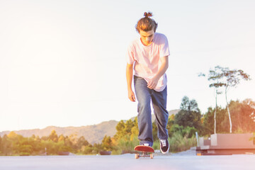 Teenage skater with pink t-shirt and jeans slides on a skateboard in a skate park - Extreme sport,...