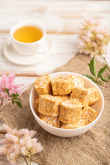 Traditional turkish delight (rahat lokum) with cup of green tea on a white wooden background. side view, close up.