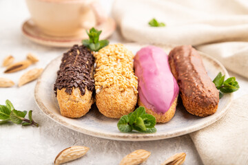 Set of eclair, traditional french dessert and cup of coffee on gray concrete background. side view, close up, selective focus.