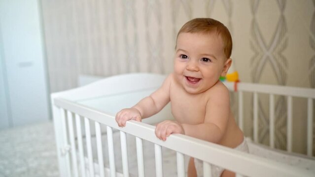 little boy toddler in diapers joyfully jumping in a crib
