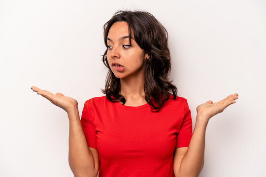 Young hispanic woman isolated on white background confused and doubtful shrugging shoulders to hold a copy space.