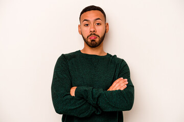 Young hispanic man isolated on white background shrugs shoulders and open eyes confused.
