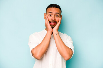 Young hispanic man isolated on blue background scared and afraid.