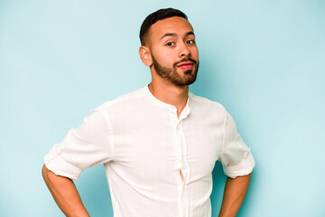 Young hispanic man isolated on blue background dreaming of achieving goals and purposes