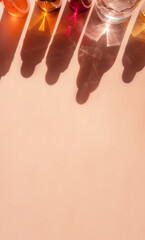 Different cosmetic glass bottles standing on beige background. Abstract pattern by shadows and illuminating reflections in the sunlight. Red, green and yellow shades. Flat lay style with copy space