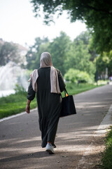 Portrait on back view of Veiled Muslim woman walking in the street - 506467527