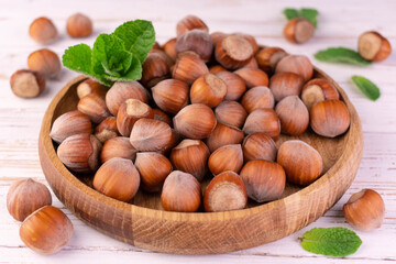 Hazelnuts in a wooden bowl on a white background.
