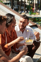 Happy group of friends eating delicious Asian street food after walking in park