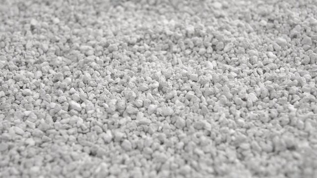 Clumping bentonite cat litter. Grey fine-grained toilet particles for pet. Macro. Rotation
