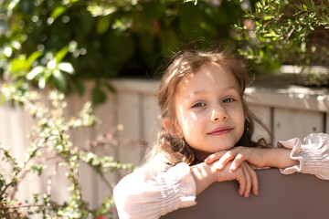 A cute little girl is resting against the backdrop of a beautiful landscape of a city park.