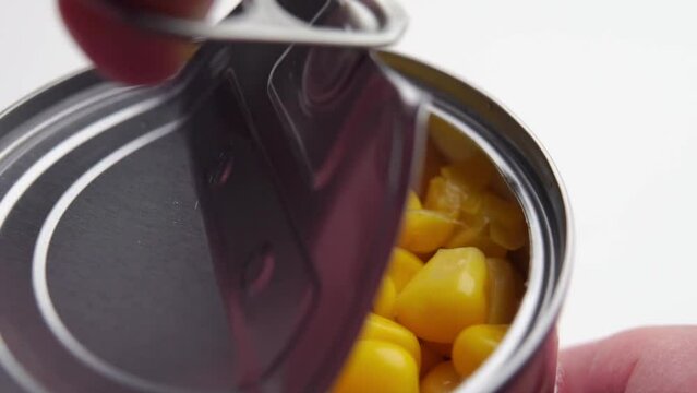 Opening a tin can with canned sweet corn kernels close-up