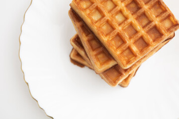 Stack of waffles on white plate with white background. Top view