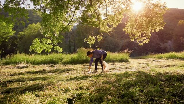 Young sporty woman in sports clothes jogging at the park and pick up garbage. Side view. The concept of volunteering and plogging.