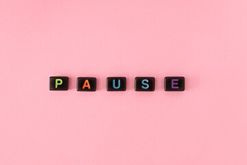 Pause button concept. Black beads on trendy pink background making word. Lifestyle phrase made of...