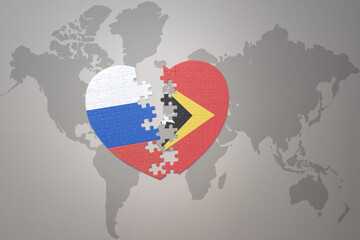 puzzle heart with the national flag of russia and east timor on a world map background. Concept.