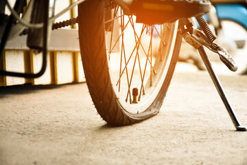 Closeup view of rear flat tire of vintage bicycle which parked on pavement beside the road. soft...
