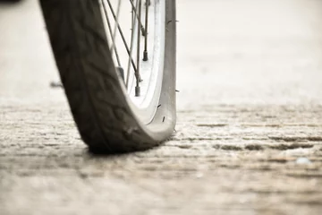 Gordijnen Close-up zicht op de achterste lekke band van een vintage fiets die op de stoep naast de weg parkeerde. zachte en selectieve focus. © Sophon_Nawit