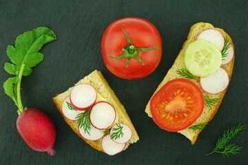A healthy sandwiches with fresh spring vegetables. Tomato and radish on a black  background. Vegetarian food. Top view, flat lay.	