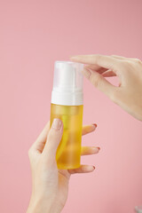 Front view of hand model holding cosmetic jar in pink background for cosmetic advertising
