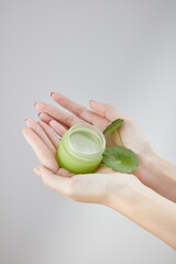  Front view of gotu kola and cosmetic jar on hand model in white background