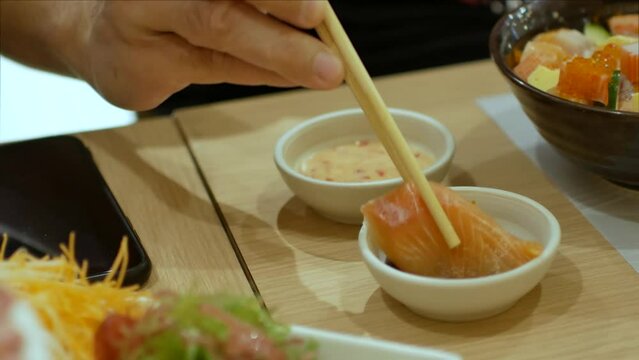 4k video of using chopctick pick slamon sashimi dipping into soy sauce, raw fish Japanese style food.