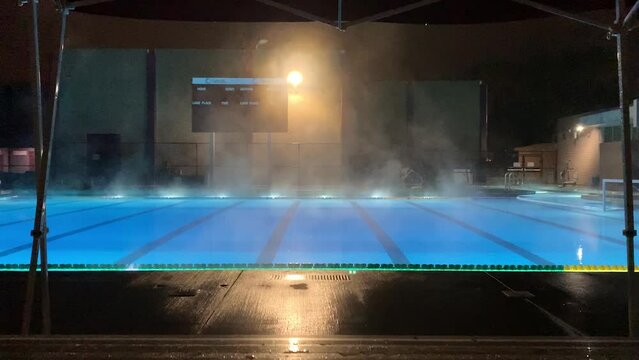 Steam rises from swimming pool at midnight