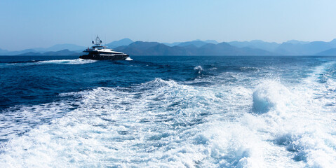 View from a high-speed ship on the blue sea with a mountainous coast in the background