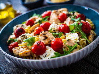 Roasted chicken nuggets, cherry tomatoes, feta cheese and fusilli  served on wooden table
 - obrazy, fototapety, plakaty