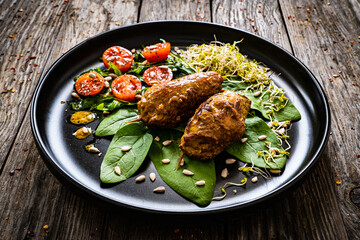Wrapped pork with greens on wooden table
