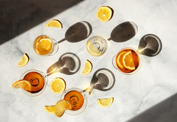 Summer cocktails in the sunlight. Fresh juicy beverages in glasses with shadows making trendy pattern. Delicious lemonade, cold tea, soda and water on gray marble background