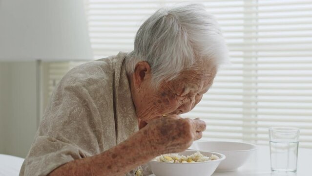 Senior Asian woman gray hair eating food at nursing home
