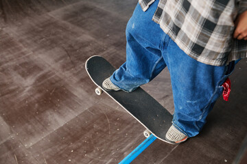 Closeup of anonymous male teenager riding skateboard on ramp at skating park, copy space