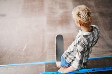 Minimal top view at teenage boy riding skateboard on ramp at skating park and doing tricks, copy...