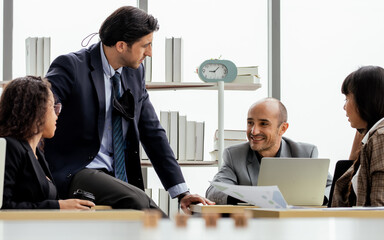 Adult smart diverse Caucasian businesspeople wearing formal suit, smiling, working, brainstorming, meeting, discussing and talking about project marketing plan in indoor modern office.