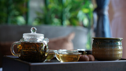 Traditional tea set tray with modern transparent pot and clear small cup in cozy Chinese room. Natural healthy hot clear drink with dried leaves give good aroma and relax for drink.