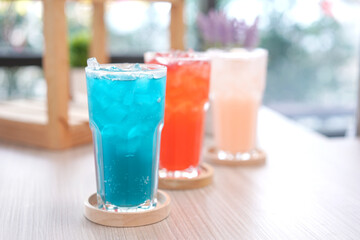 Refreshing cold beverage for summer on ice. Colorful summer drink in tall glass with wood saucer for hot day and party.