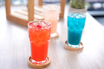 Refreshing cold beverage for summer on ice. Colorful summer drink in tall glass with wood saucer for hot day and party.