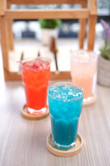 Refreshing cold beverage for summer on ice. Colorful summer drink in tall glass with wood saucer for hot day and party.
