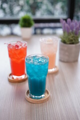 Refreshing cold beverage for summer on ice. Colorful summer drink in tall glass with wood saucer for hot day and party.