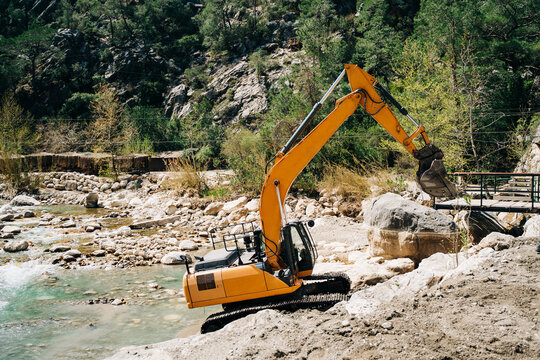 Heavy machinery dragline excavator digging ground in the mountain canyon. Digger ditcher working on a gold mine in the mountains. Mining equipment.