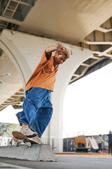 Full length shot of teenager in motion doing skateboarding tricks in urban skatepark