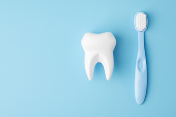 Teeth care and dental hygiene. Toy tooth and toothbrush on blue background, flat lay. Dental concept