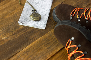 View from above of a pair of brown hiking boots, a map and a compass needed for a nature trail. Concept of holidays and freedom in the open air.