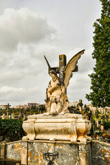 gro&szlig;er Engel kniet vor einem Kreuz
eines Friedhofes auf Spaniens Insel Mallorca