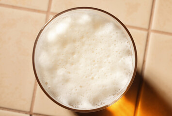 Glass of fresh lager beer with White fresh Foam on table. Beer foam top view. Bubble froth of beer