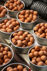 Bunch of brown organic and vegetarian eggs in multiple utensils for sale in market during festival for easter