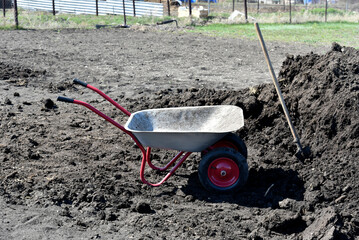 Iron garden cart with soil in the garden. Fertilization of the earth. Manure.