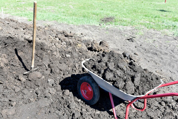 Iron garden cart with soil in the garden. Fertilization of the earth. Manure.