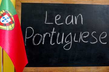 Fototapeta na wymiar Flag of Portugal and the inscription learn Portuguese on the blackboard.